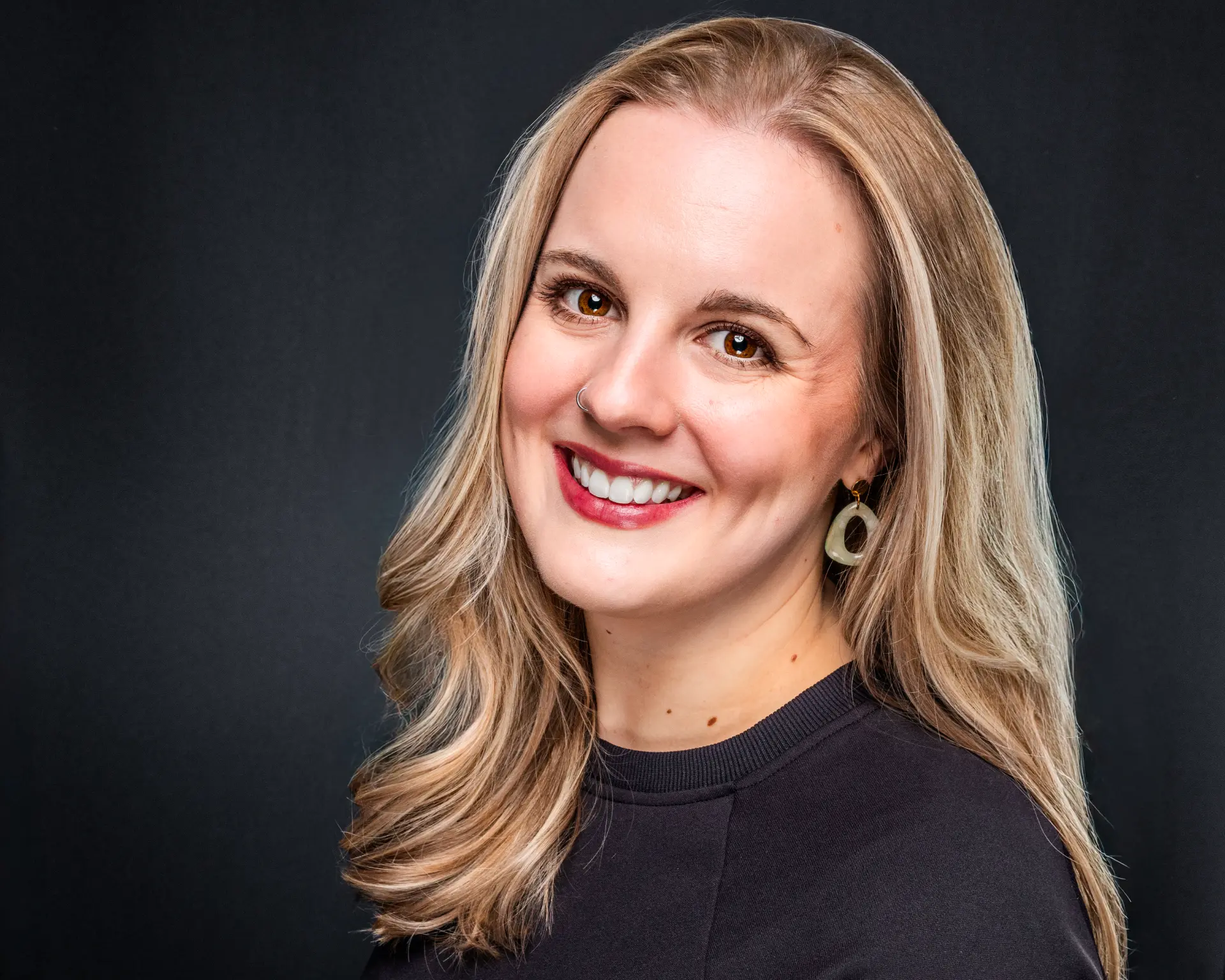 Studio headshot of a smiling professional woman with long blonde hair
